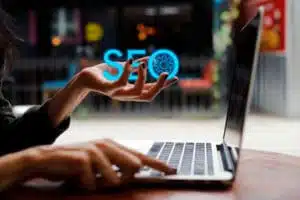 SEO neon text on a womans left hand with her right hand on a laptop -technical SEO