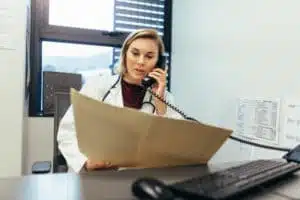 Doctor reading medical records and talking on telephone using a call tracking software