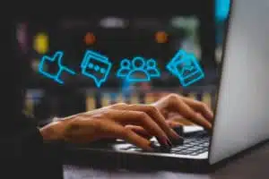 neon social media content icons hovering over hands on a laptop