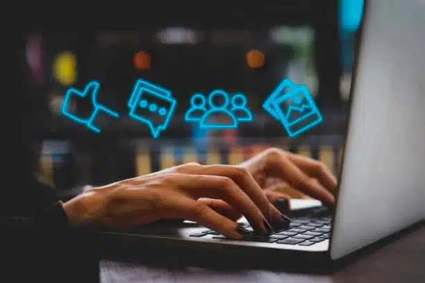 neon social media content icons hovering over hands on a laptop