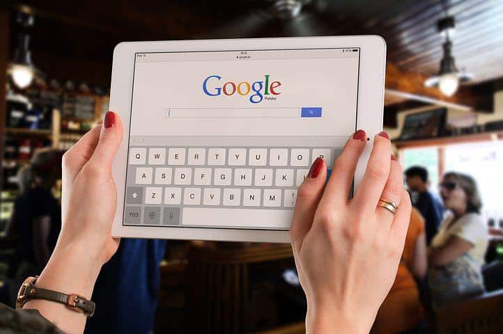 Image of woman holding her smart gadget trying to d a keyword search on google