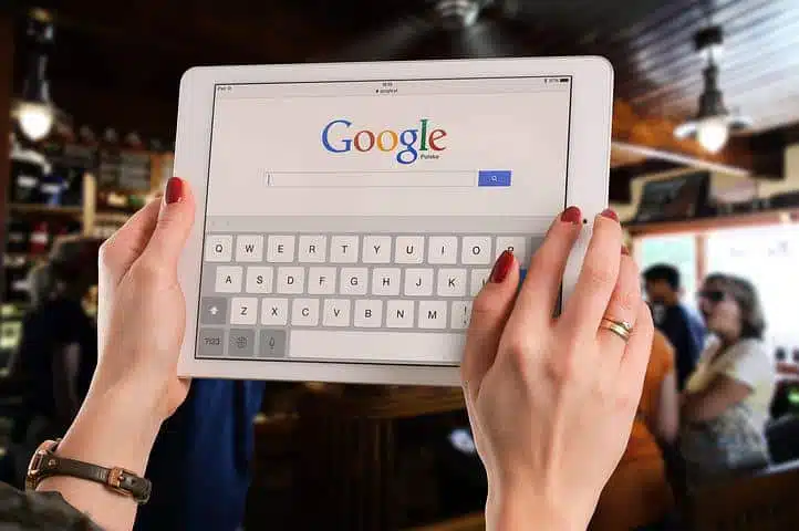 Image of woman holding her smart gadget trying to d a keyword search on google 